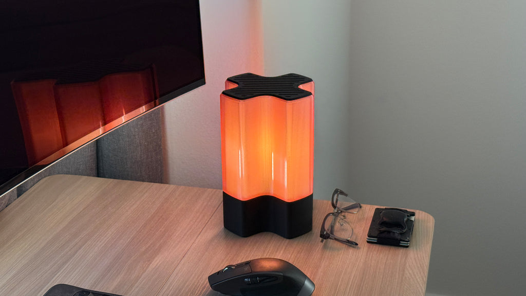 Front three-quarter view of Nebu 3D printed modern tabletop lamp in Cozy Pink shade, shown on with soft ambient light